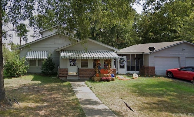 view of front of home featuring a sunroom, a garage, a front yard, and brick siding