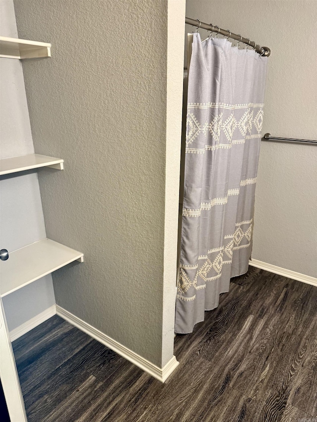 bathroom featuring wood finished floors, baseboards, and a shower with shower curtain
