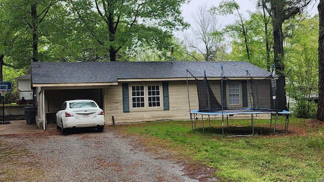 view of front of property featuring an attached garage, a trampoline, and dirt driveway