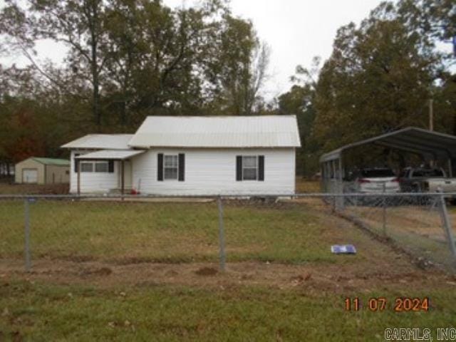 view of front of home featuring a front yard, a detached carport, and fence