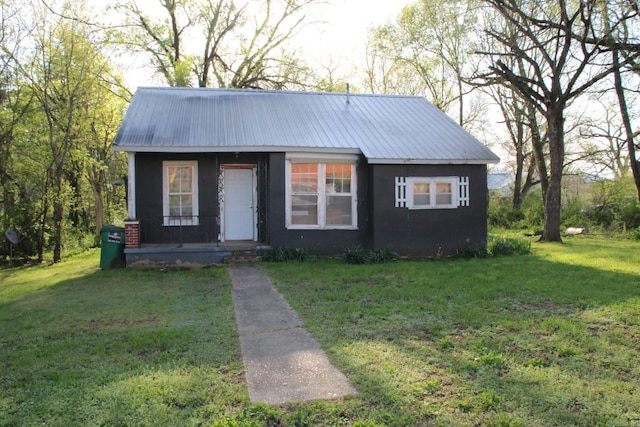 bungalow with a front yard, a porch, metal roof, and stucco siding