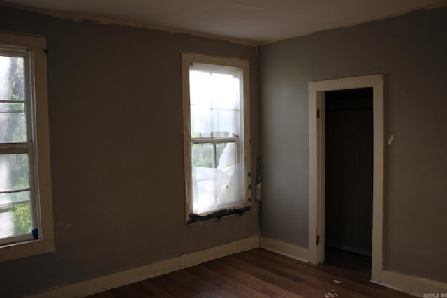spare room with dark wood-style floors, baseboards, and a healthy amount of sunlight