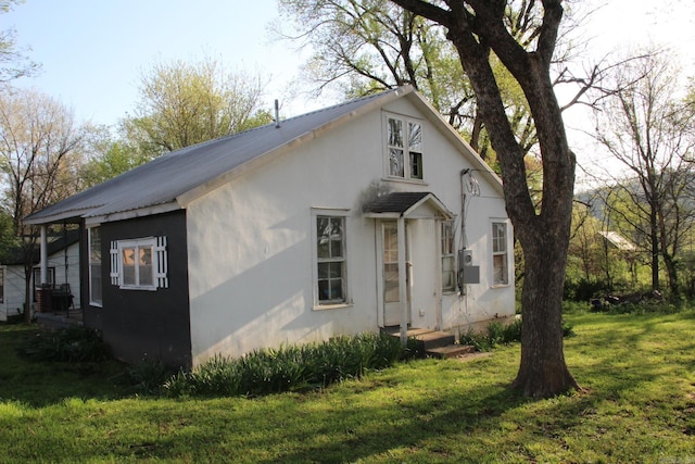 view of front of house with metal roof, stucco siding, and a front lawn