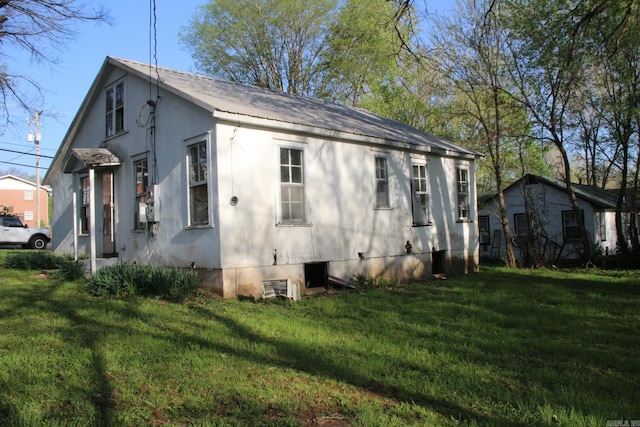 view of side of property featuring metal roof and a lawn