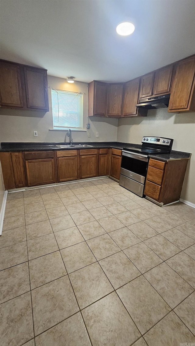 kitchen featuring under cabinet range hood, dark countertops, a sink, light tile patterned flooring, and electric range