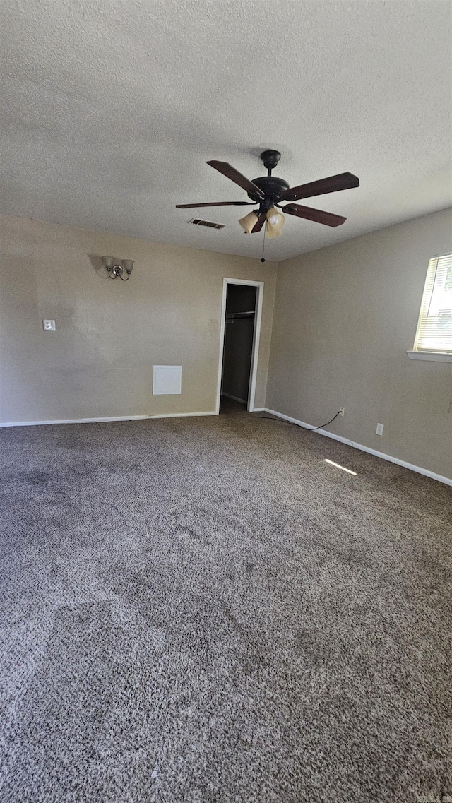 carpeted empty room featuring baseboards, a ceiling fan, visible vents, and a textured ceiling