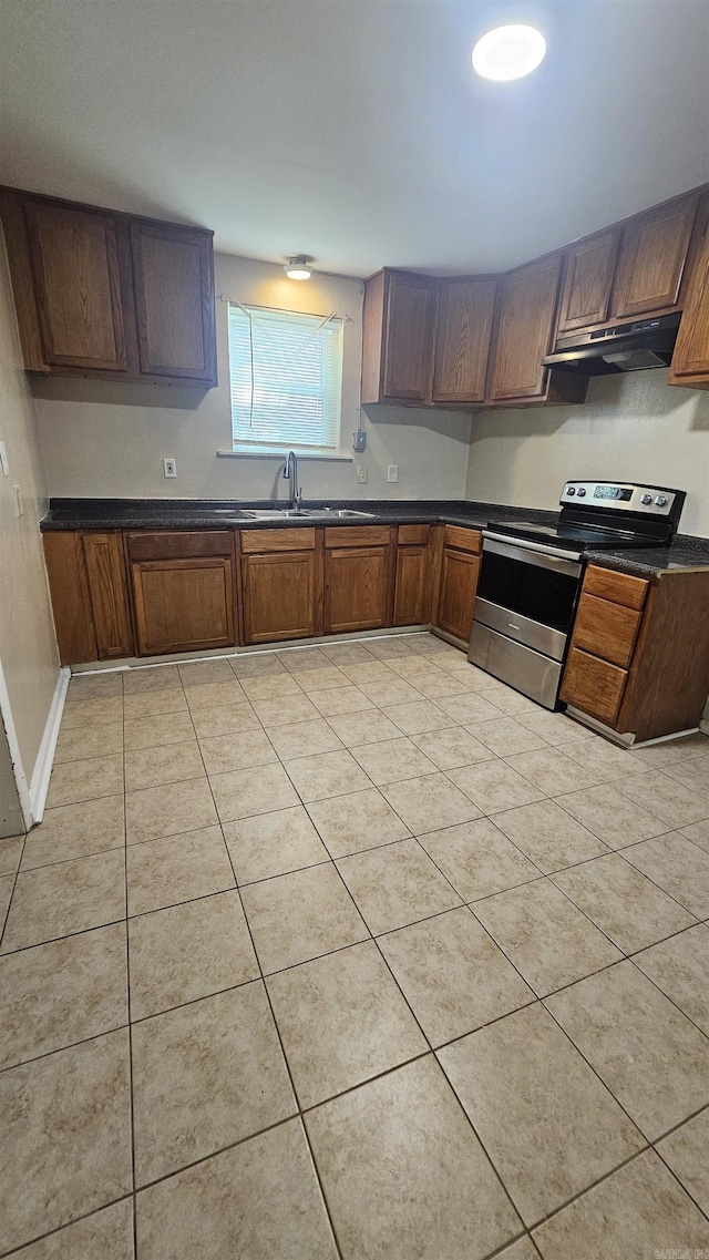 kitchen with dark countertops, stainless steel electric stove, under cabinet range hood, and light tile patterned floors