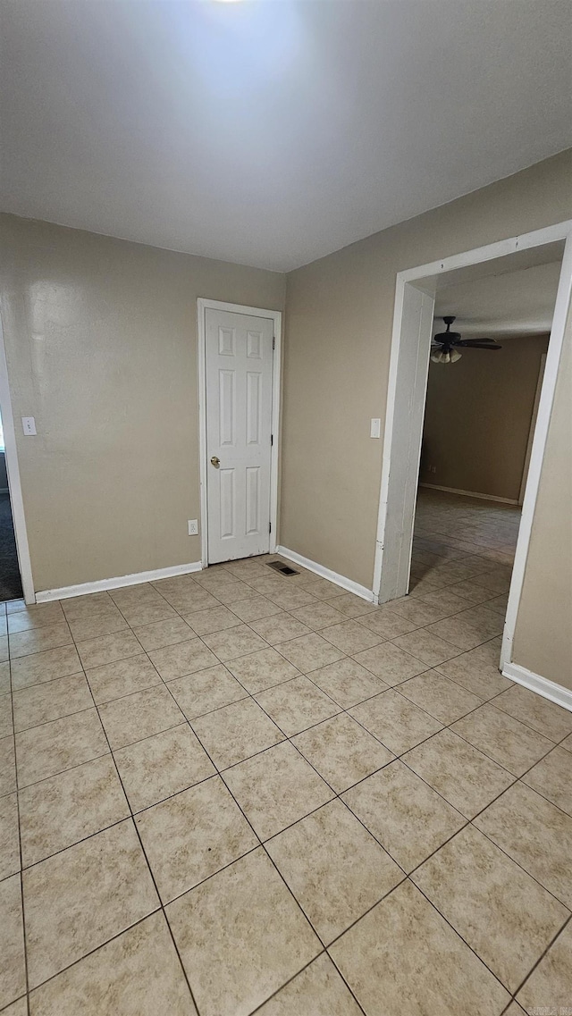 empty room featuring baseboards, a ceiling fan, visible vents, and light tile patterned flooring