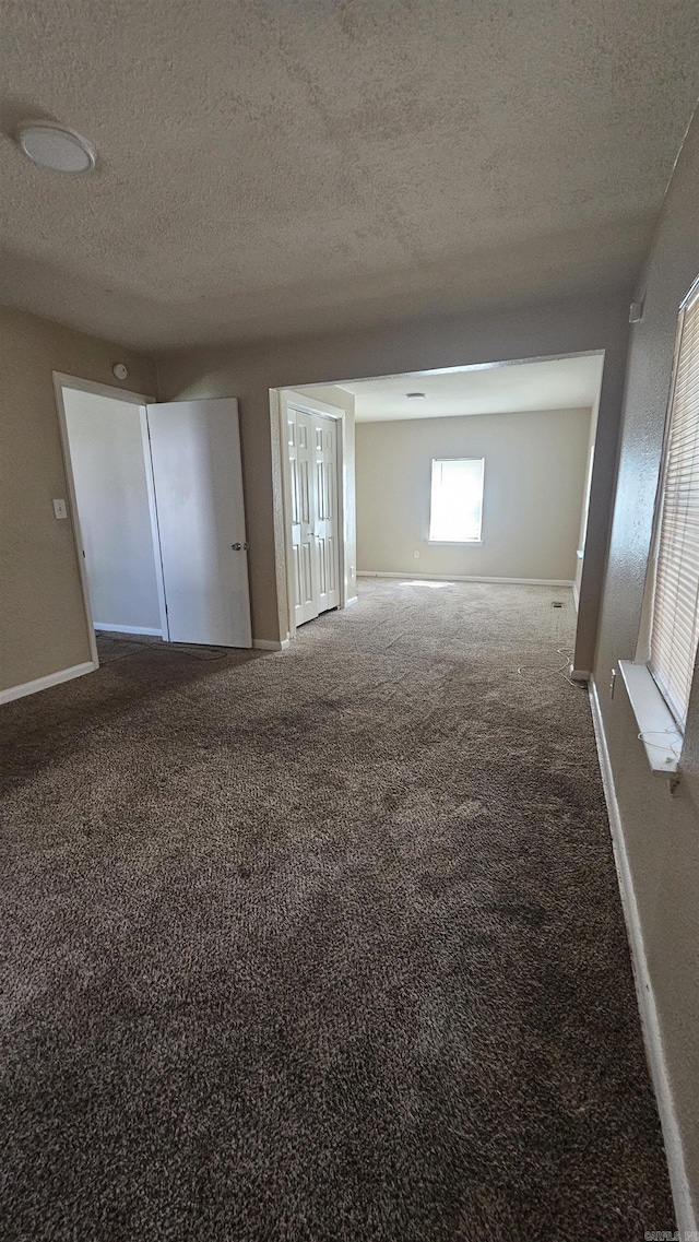 carpeted empty room with baseboards and a textured ceiling