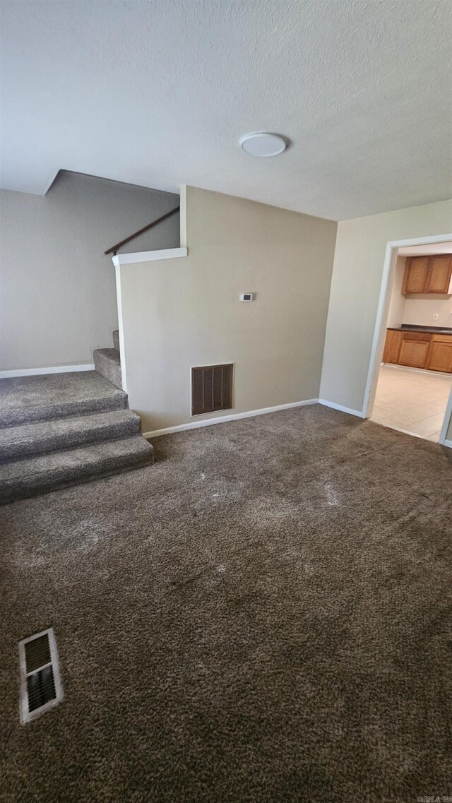 interior space with carpet flooring, a textured ceiling, and visible vents