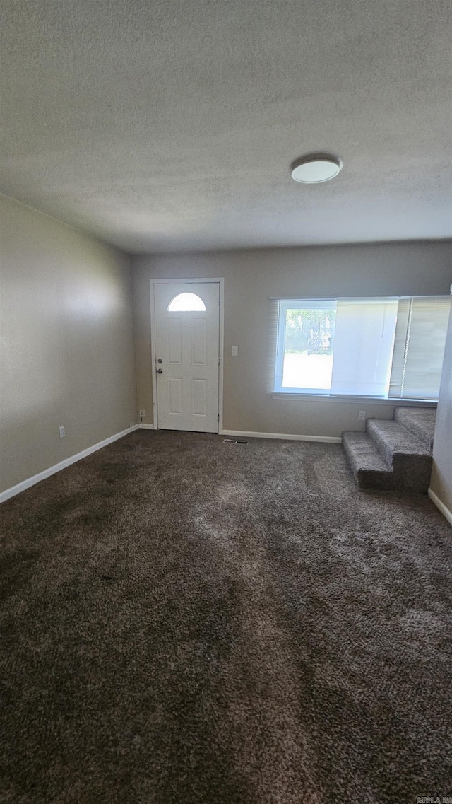 carpeted entrance foyer featuring baseboards and a textured ceiling