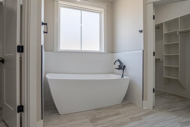 240 Michelle Dr, Beebe, AR 72012 - bathroom featuring a walk in closet, wainscoting, and a soaking tub
