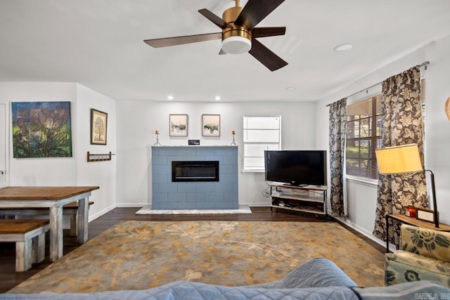 living area with wood finished floors, a tiled fireplace, and baseboards