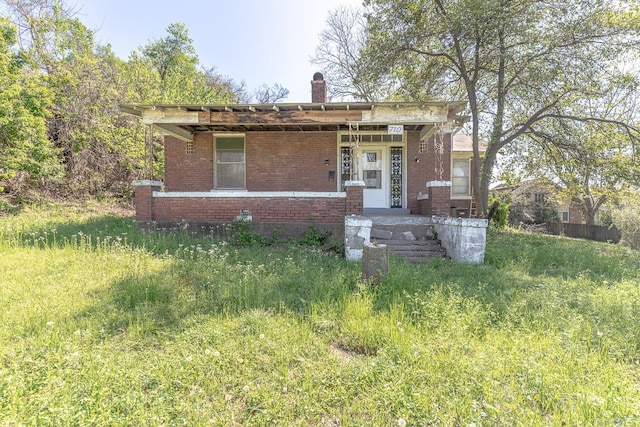 bungalow with brick siding and a chimney