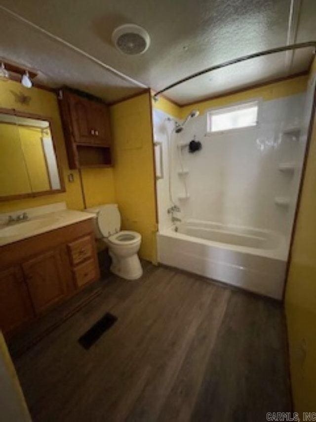bathroom featuring visible vents, toilet, vanity, wood finished floors, and shower / tub combination