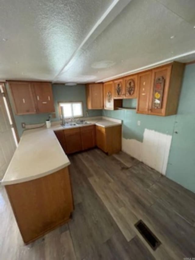 kitchen featuring visible vents, light countertops, a textured ceiling, brown cabinetry, and wood finished floors