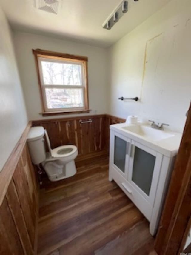 bathroom with visible vents, toilet, wainscoting, wood finished floors, and vanity