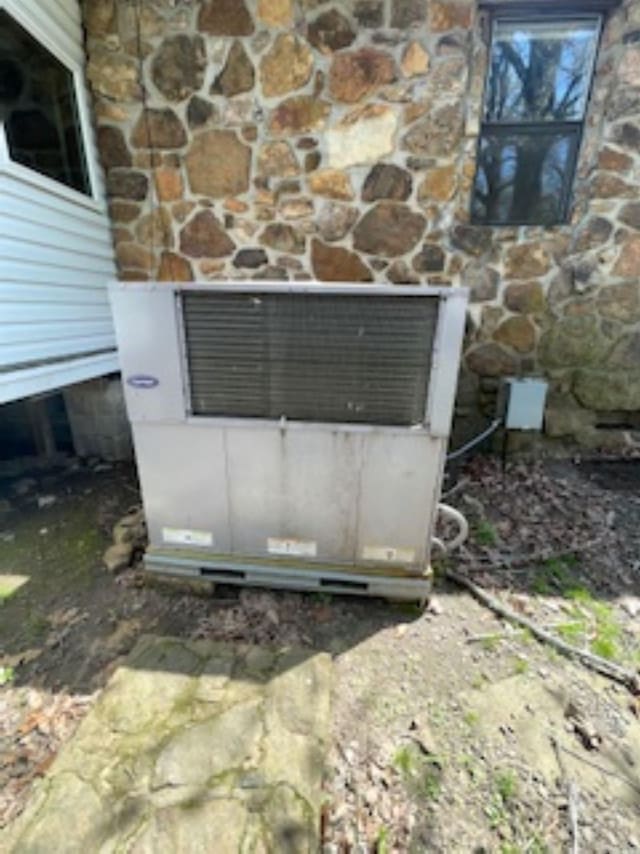 exterior details featuring stone siding and heating unit