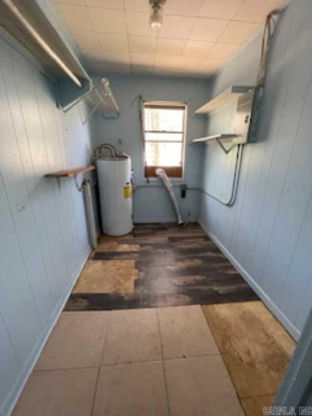 laundry room with laundry area, wood walls, and water heater