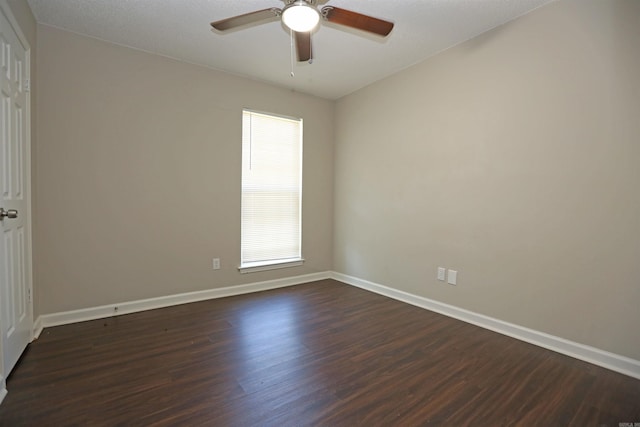 empty room featuring dark wood-style flooring, baseboards, and ceiling fan