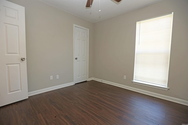 unfurnished room featuring ceiling fan, baseboards, and dark wood finished floors