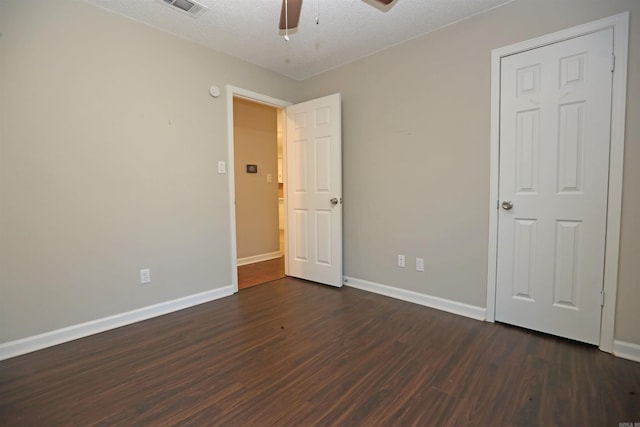 unfurnished bedroom with baseboards, dark wood finished floors, a textured ceiling, visible vents, and ceiling fan