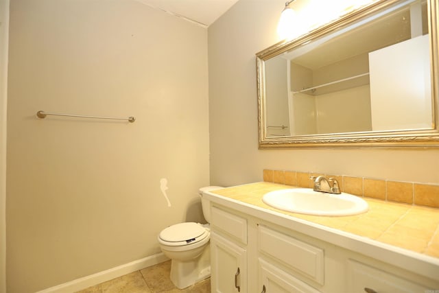 bathroom featuring tile patterned floors, vanity, baseboards, and toilet