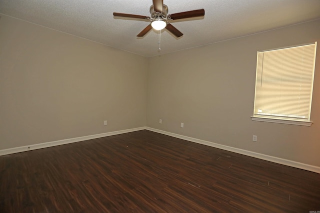 spare room featuring a textured ceiling, dark wood-style flooring, baseboards, and a ceiling fan
