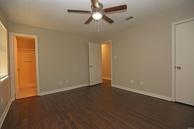unfurnished bedroom with dark wood-type flooring, visible vents, baseboards, and a textured ceiling
