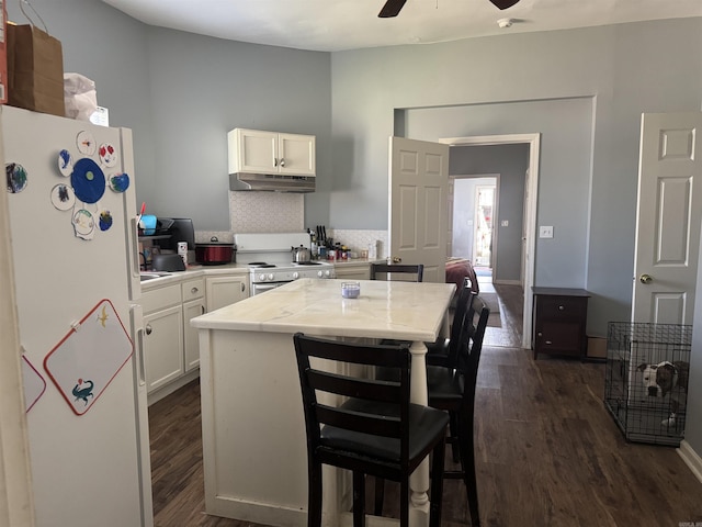 kitchen with dark wood-type flooring, white cabinets, white appliances, and under cabinet range hood