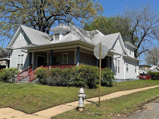 view of front of house featuring a porch, a shingled roof, and a front yard