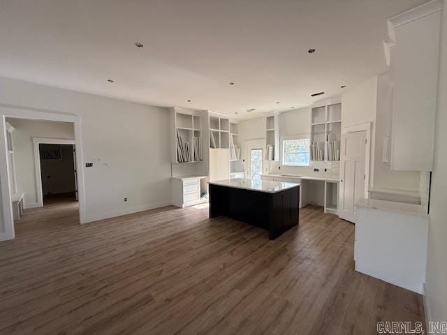kitchen with baseboards, a center island, light countertops, open shelves, and wood finished floors