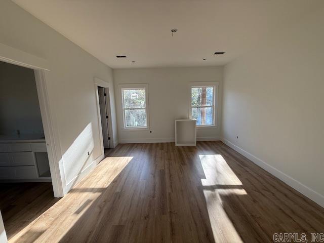 interior space with wood finished floors, baseboards, and visible vents