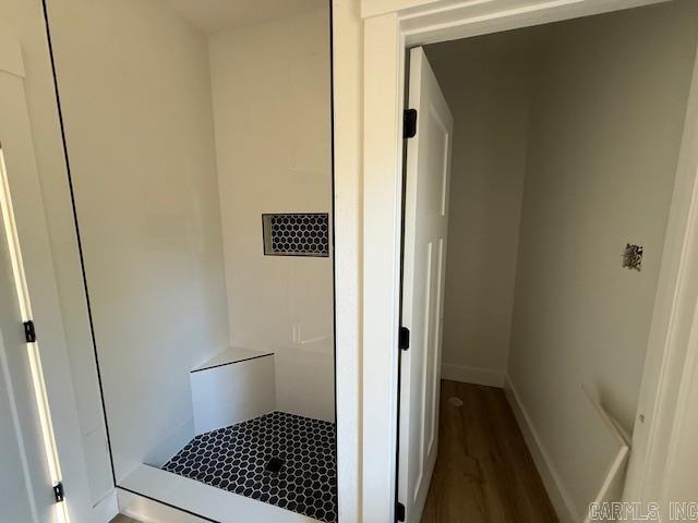 bathroom featuring baseboards, a shower, and wood finished floors