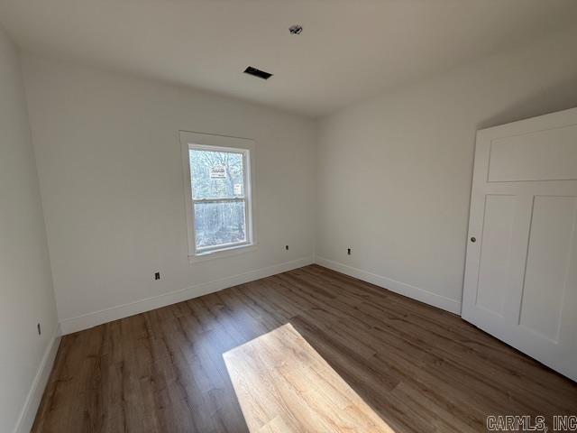 spare room with wood finished floors, baseboards, and visible vents