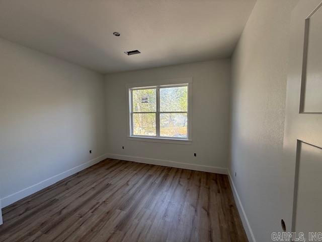 unfurnished room with wood finished floors, baseboards, and visible vents