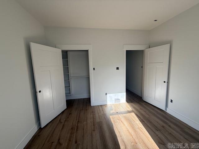 unfurnished bedroom featuring a closet, baseboards, and wood finished floors