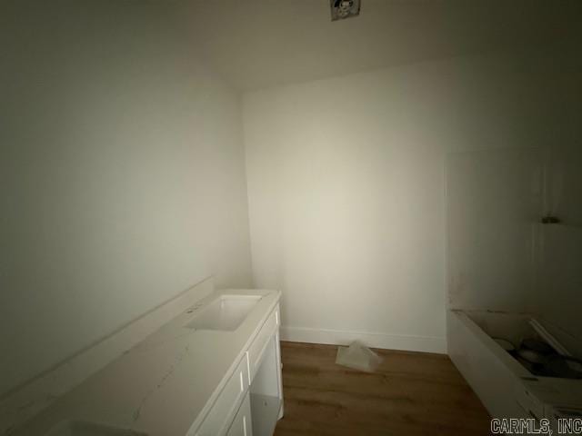 bathroom featuring a bathtub, vanity, baseboards, and wood finished floors