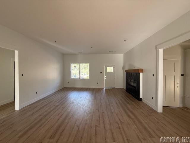 unfurnished living room with a glass covered fireplace, baseboards, and wood finished floors