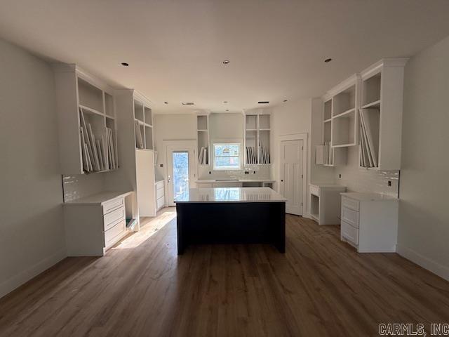 kitchen with a center island, baseboards, open shelves, and dark wood finished floors