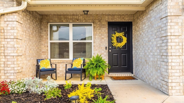 view of exterior entry with brick siding and covered porch