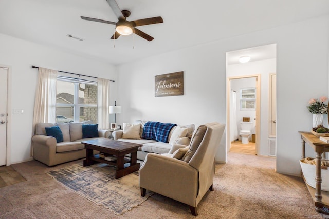living area featuring light carpet, a ceiling fan, and visible vents
