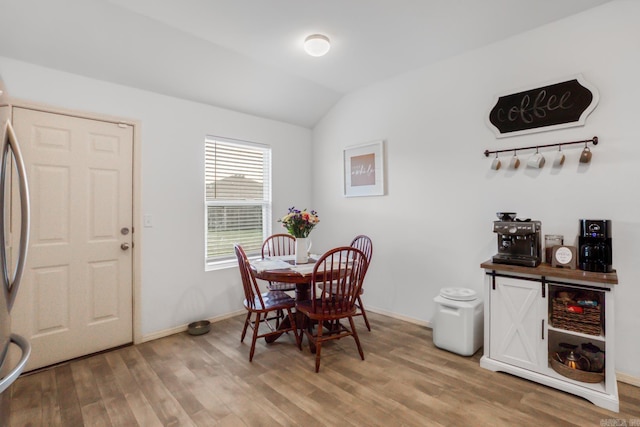 dining area with light wood-style flooring, baseboards, and lofted ceiling