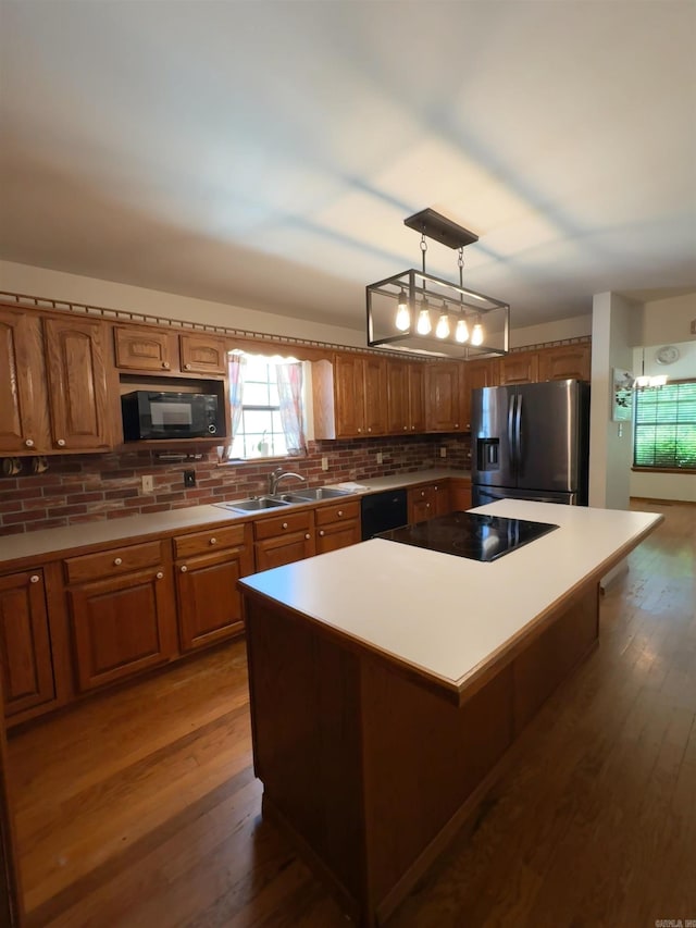 kitchen with brown cabinetry, a kitchen island, backsplash, and black appliances