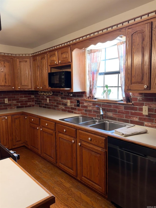 kitchen featuring black microwave, dishwasher, brown cabinetry, and a sink