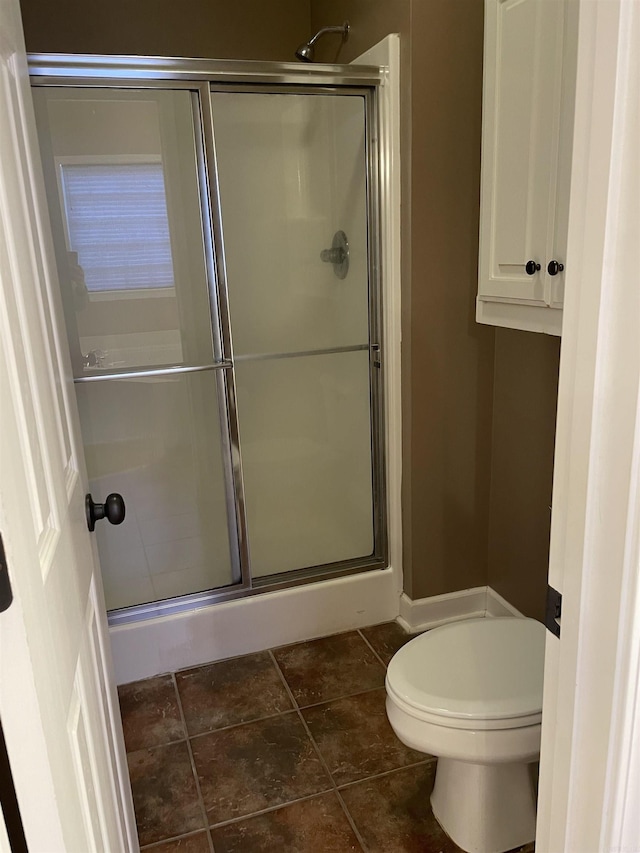 bathroom featuring toilet and a shower stall