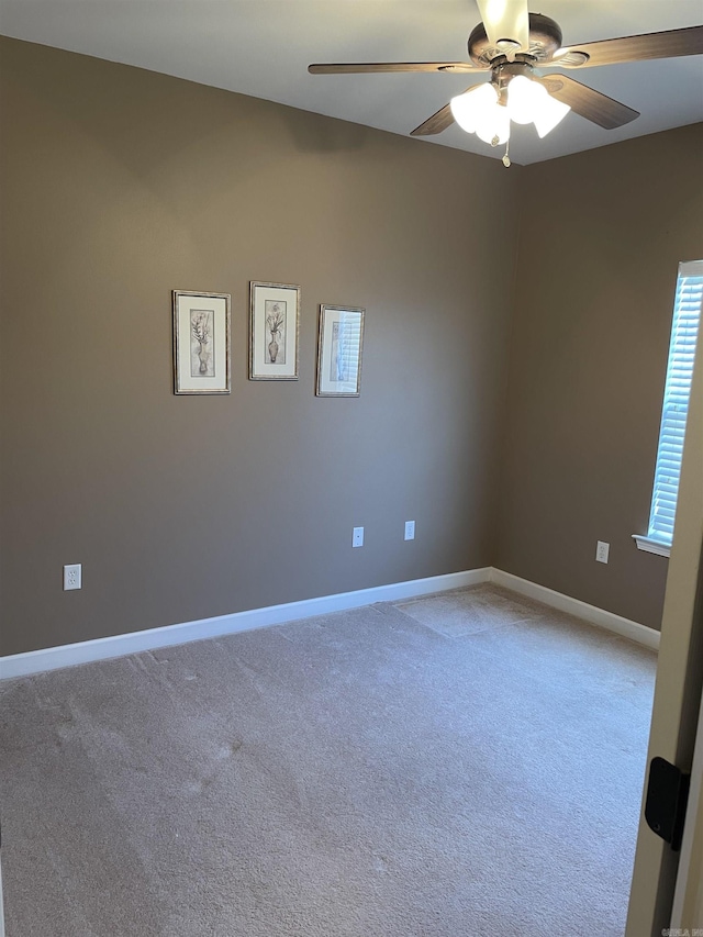 spare room with light colored carpet, baseboards, and a ceiling fan