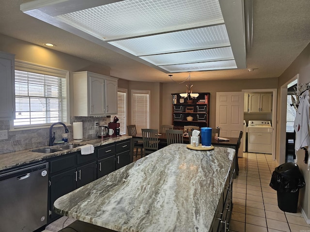 kitchen with tasteful backsplash, light tile patterned floors, a sink, stainless steel dishwasher, and light stone counters