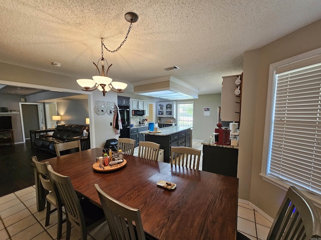 dining room with a chandelier, visible vents, light tile patterned flooring, and a textured ceiling