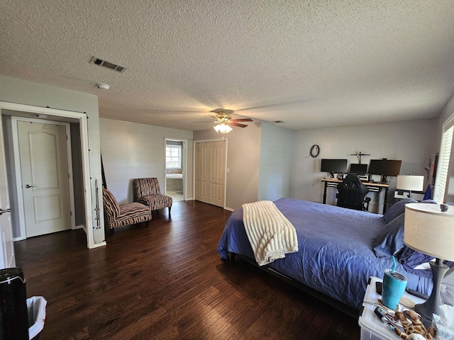 bedroom with a textured ceiling, a closet, a ceiling fan, visible vents, and wood finished floors